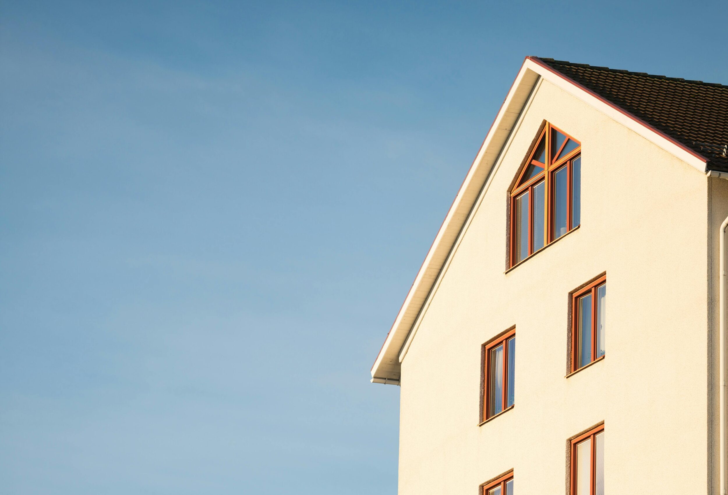 Minimalist modern residential building facade against clear blue sky.